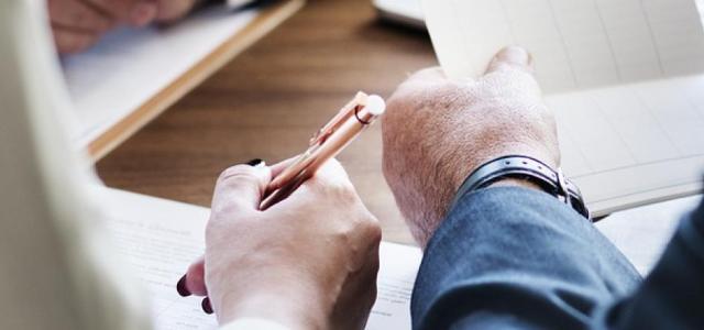 two adults holding papers while sitting at a desk